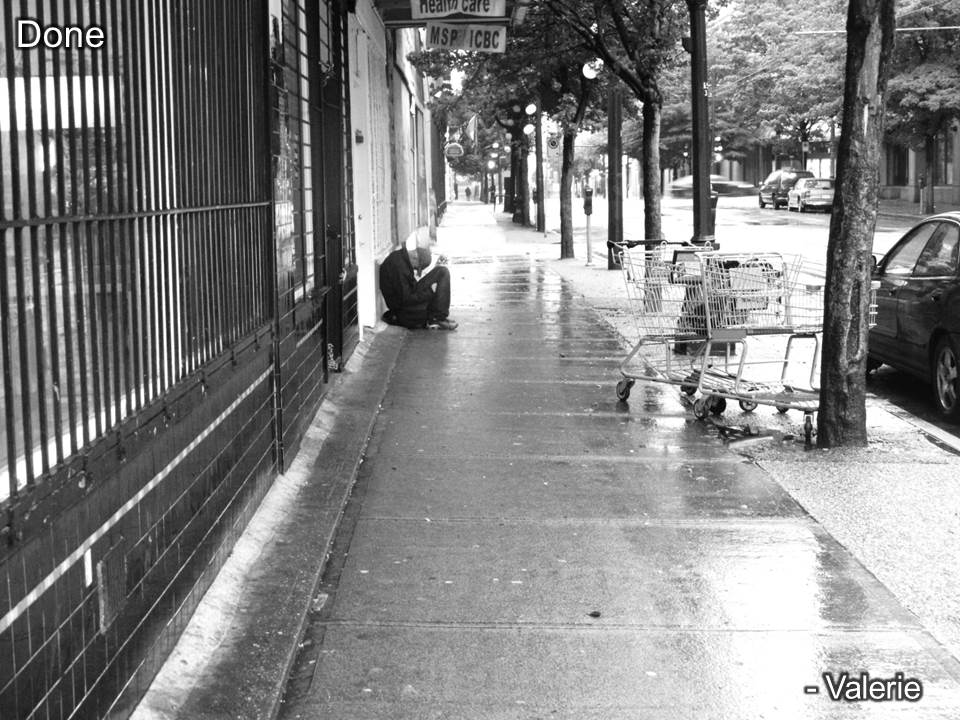 Homeless man sitting on the sidewalk in the rain